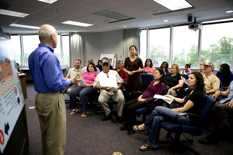 man speaking at a town hall meeting 768x512